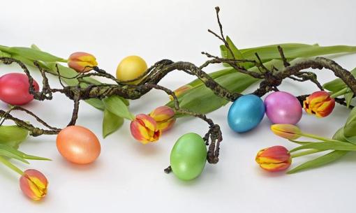 Uova colorate e tulipani su rami intrecciati.