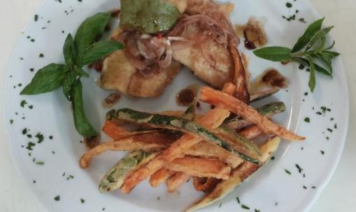 Piatto di carne con verdure fritte e erbe aromatiche.