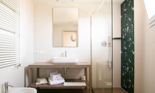Bagno moderno con doccia, lavabo e decorazioni verdi lussureggianti.
