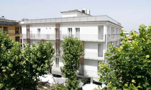 Edificio bianco moderno circondato da alberi verdi, atmosfera serena e luminosa.